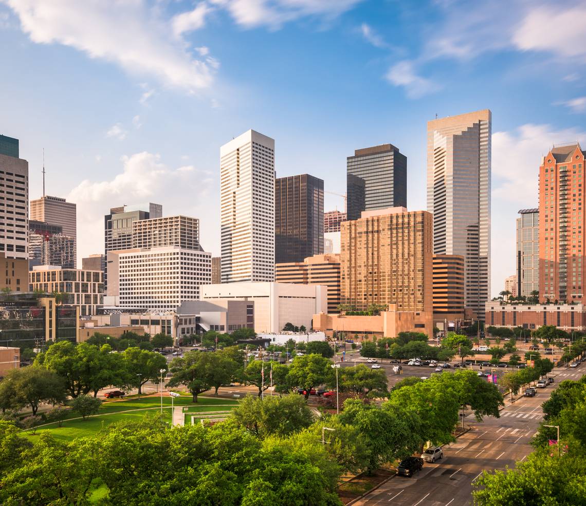 Houston skyline with downtown office towers rising above green park space.