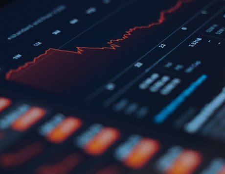Dark financial charts and stock data glowing on a trading screen.